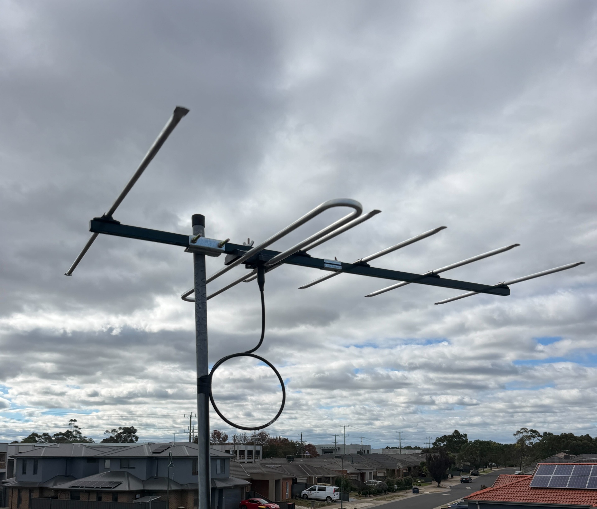 New Australian-made digital antenna installed on a mast in Melton with cloudy sky and surrounding rooftops in the background